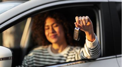 Woman holding car keys through a car window.